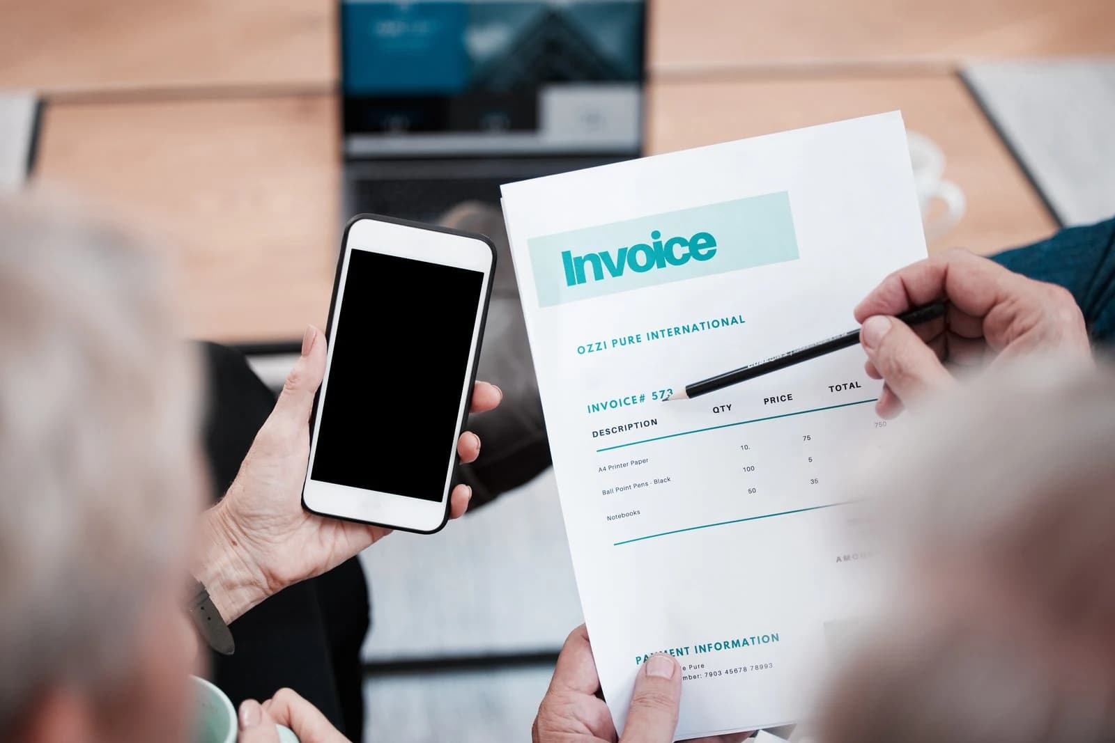 En faktura kontrolleres med en mobiltelefon ved siden av